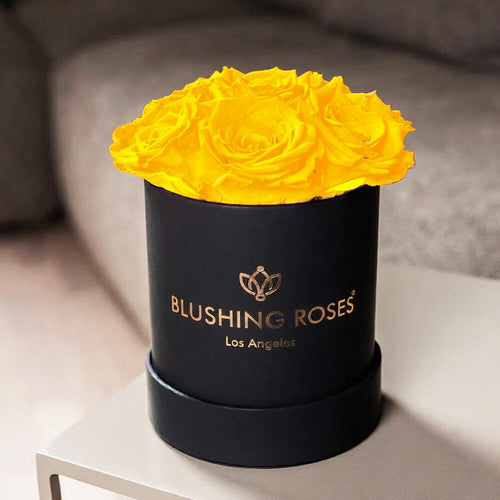 YELLOW ROSES IN A BLACK BOX WITH BLUSIHING ROSES BRANDING ON LABEL