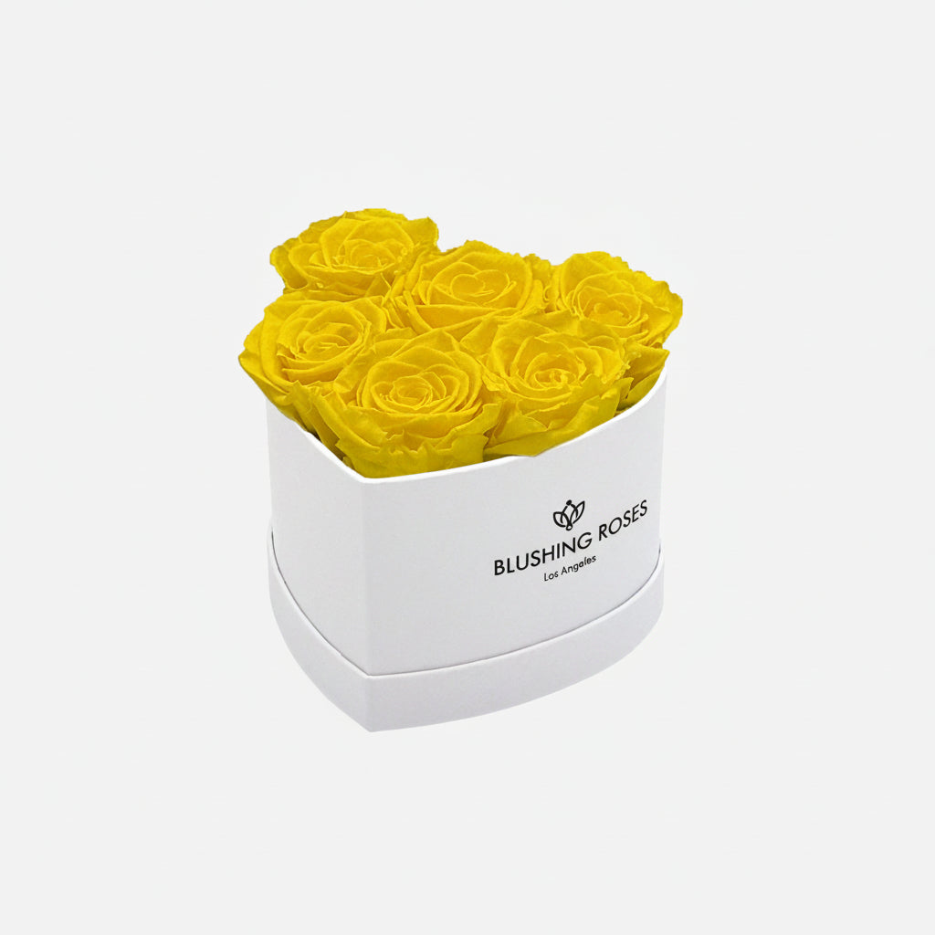 Heart-shaped box with yellow roses and 'BLUSHING Roses' branding on a white background